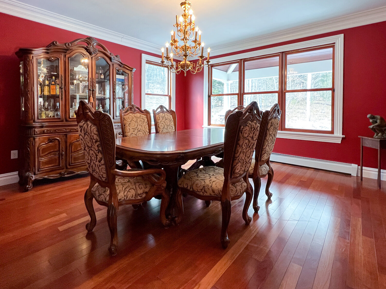 The formal dining room is dressed with cherry-red walls and a rich cherry floor.